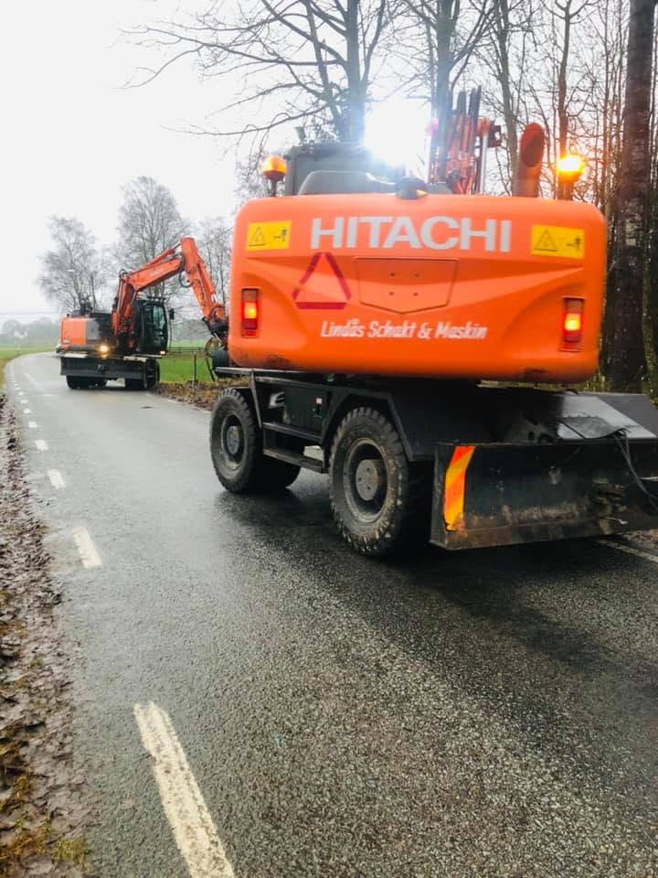 Hitachi-hjulgrävare med Lindås Schakt & Maskin på motvikten, i konvoj på landsväg