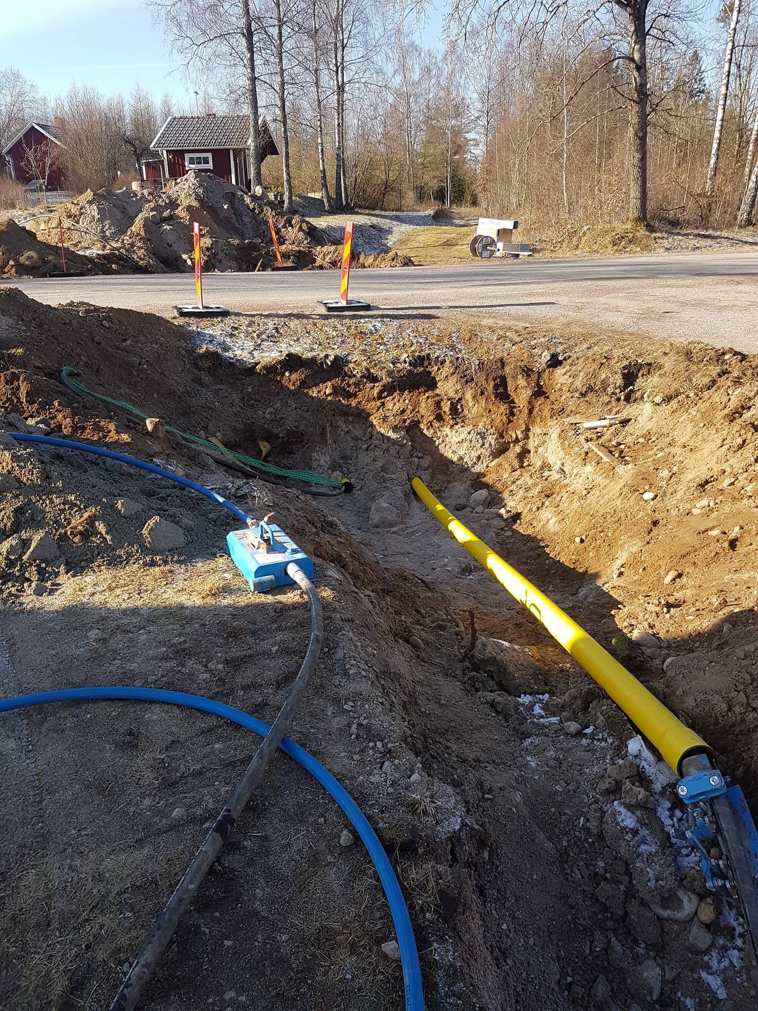 Gult skyddsrör och blåsmaskin i schakt vid väg, rörtryckning i Ljungby